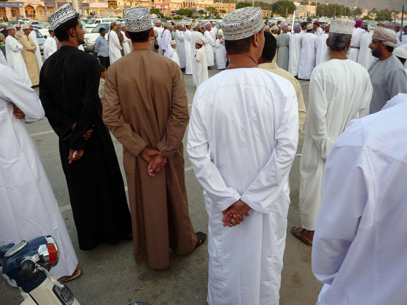 Die Männer tragen ihre traditionelle, alltägliche Kleidung: eine dishdasha (ein langärmliges, hemdähnliches Gewand), die Kopfbedeckung: eine Kumah (Oman).