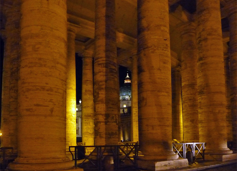 Blick durch die Säulenzeilen am Petersplatz auf den Petersdom (Italien).